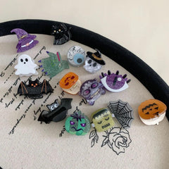 Collection of Halloween-themed hair clips including a witch hat, ghost, bat, pumpkin, skull, cat, spiderweb, and monster