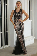 Woman wearing a black sleeveless mermaid gown with gold sequin embellishments and a sheer tulle hem.