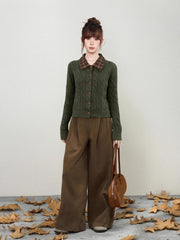 Woman holding a brown handbag and wearing a green cable knit cardigan