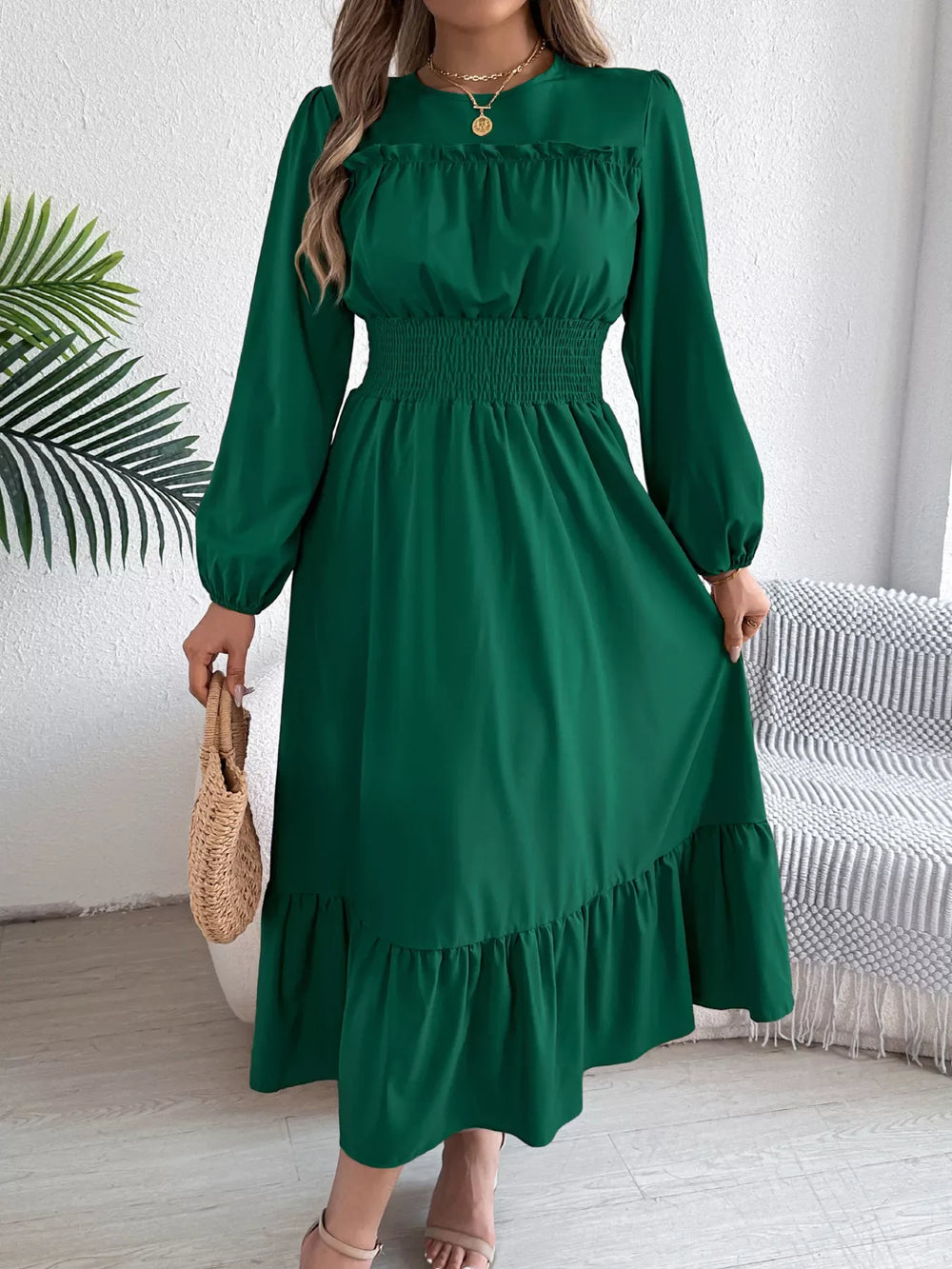 woman holding a straw bag while wearing a long green dress