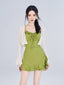 Woman wearing a green ruffled mini dress with a white sheer cardigan