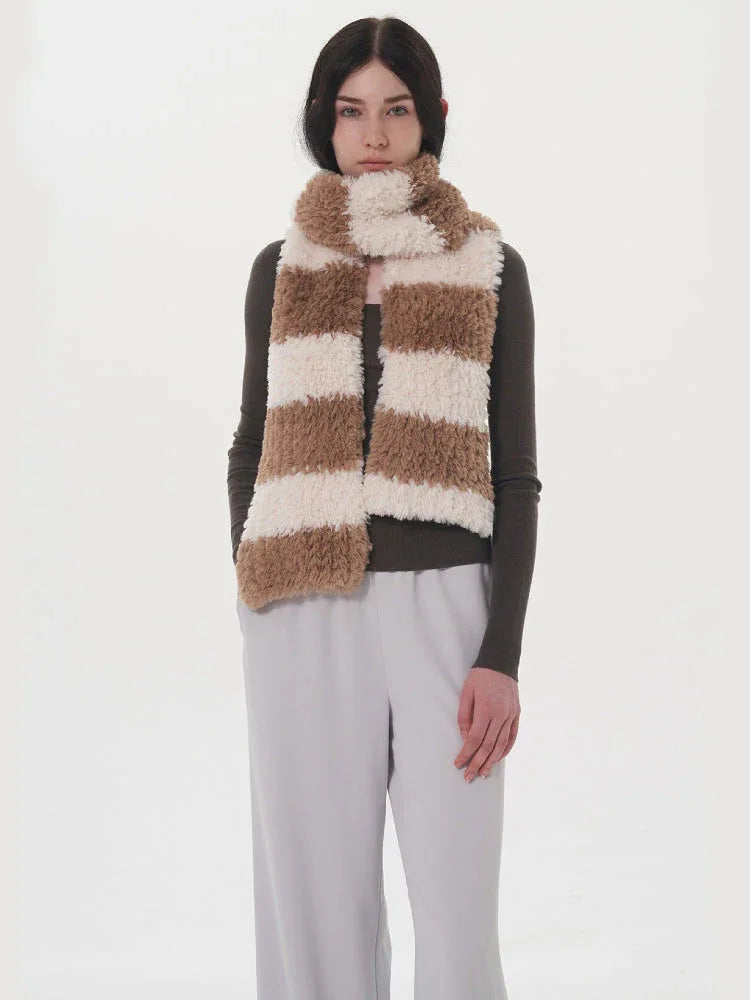 Model wearing a grey long-sleeved top, light grey pants, and a brown and white striped fuzzy scarf.