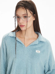Close-up of a model's face wearing a light blue fuzzy knit collared v-neck sweater and silver-rimmed glasses.