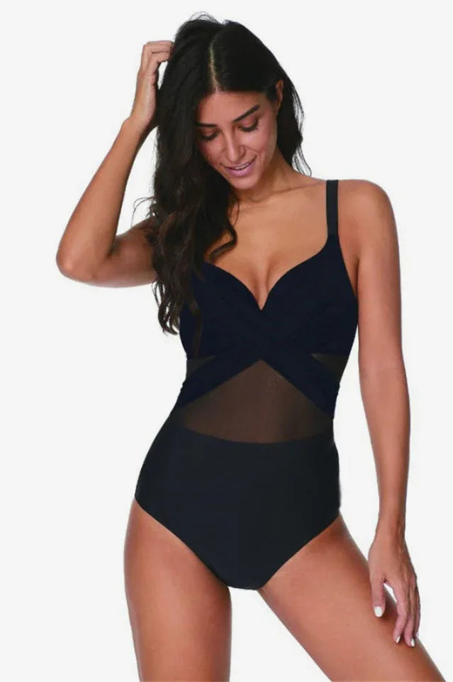 Woman wearing a black one-piece swimsuit with mesh detailing
