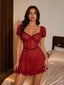 Woman wearing a red sheer mesh babydoll dress with ruffle trim and puffed sleeves, standing in a bedroom.
