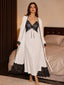 Front view of a woman wearing a white two-piece sleepwear set with black lace trim, consisting of a maxi nightdress and a matching long robe.
