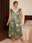 Front view of a woman wearing a green floral satin nightgown with lace trim and ruffle sleeves.