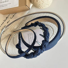 Two denim headbands, one padded and one with knotted fabric and clips, in a metal basket.