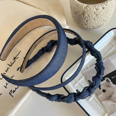 Two denim headbands, one padded and one with knotted fabric and clips, on a cloth.