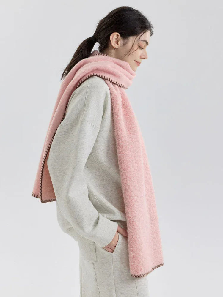 Woman in profile wearing a pink fuzzy knit scarf and grey sweatshirt