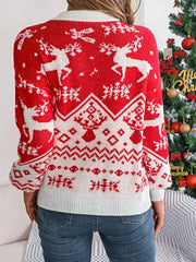Back view of a woman wearing a red and white Christmas sweater with a reindeer pattern, standing in front of a Christmas tree.