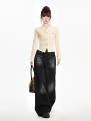 Full body shot of a woman wearing a cream cable knit cropped cardigan with black wide-leg jeans, a black belt, and a black fur bag