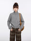Woman wearing a grey zip-up knit sweater with a high neck and brown plaid wide-leg pants, with a brown crossbody bag, front view.