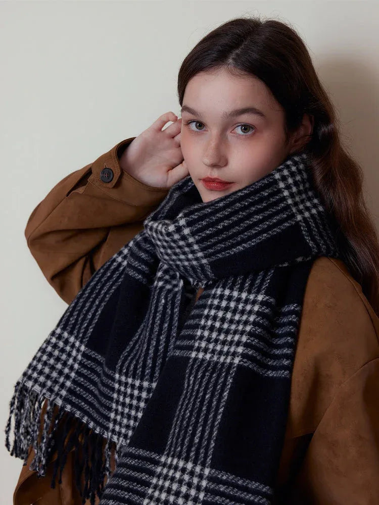 Woman adjusting a black and white plaid scarf with fringe detail