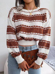 Woman wearing a brown and white striped cropped knit sweater, light wash jeans, and holding a brown clutch with fringe detail.