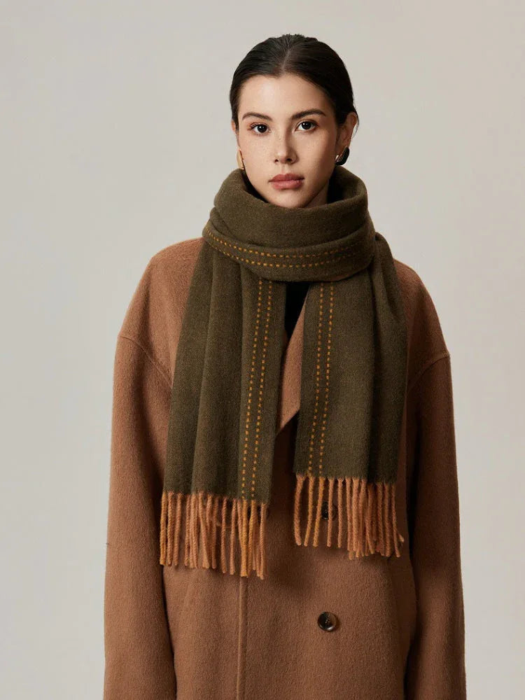 Woman wearing a green scarf with orange detailing and a tan coat