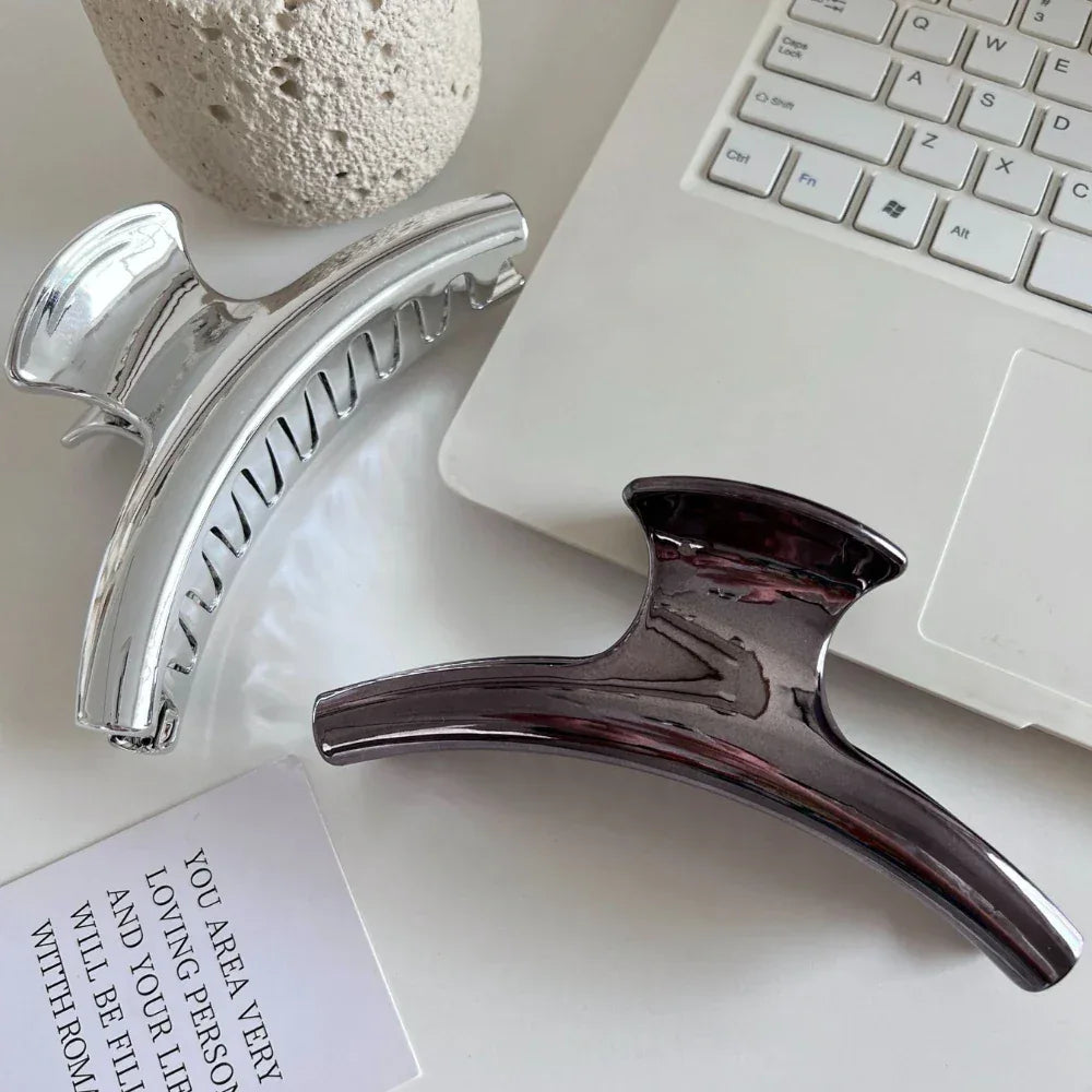 Silver and dark grey metallic claw clips positioned near a laptop keyboard