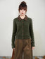 Woman wearing a green cable knit cardigan with a plaid collar