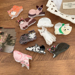 A collection of cat-shaped hair clips arranged on a wooden surface.