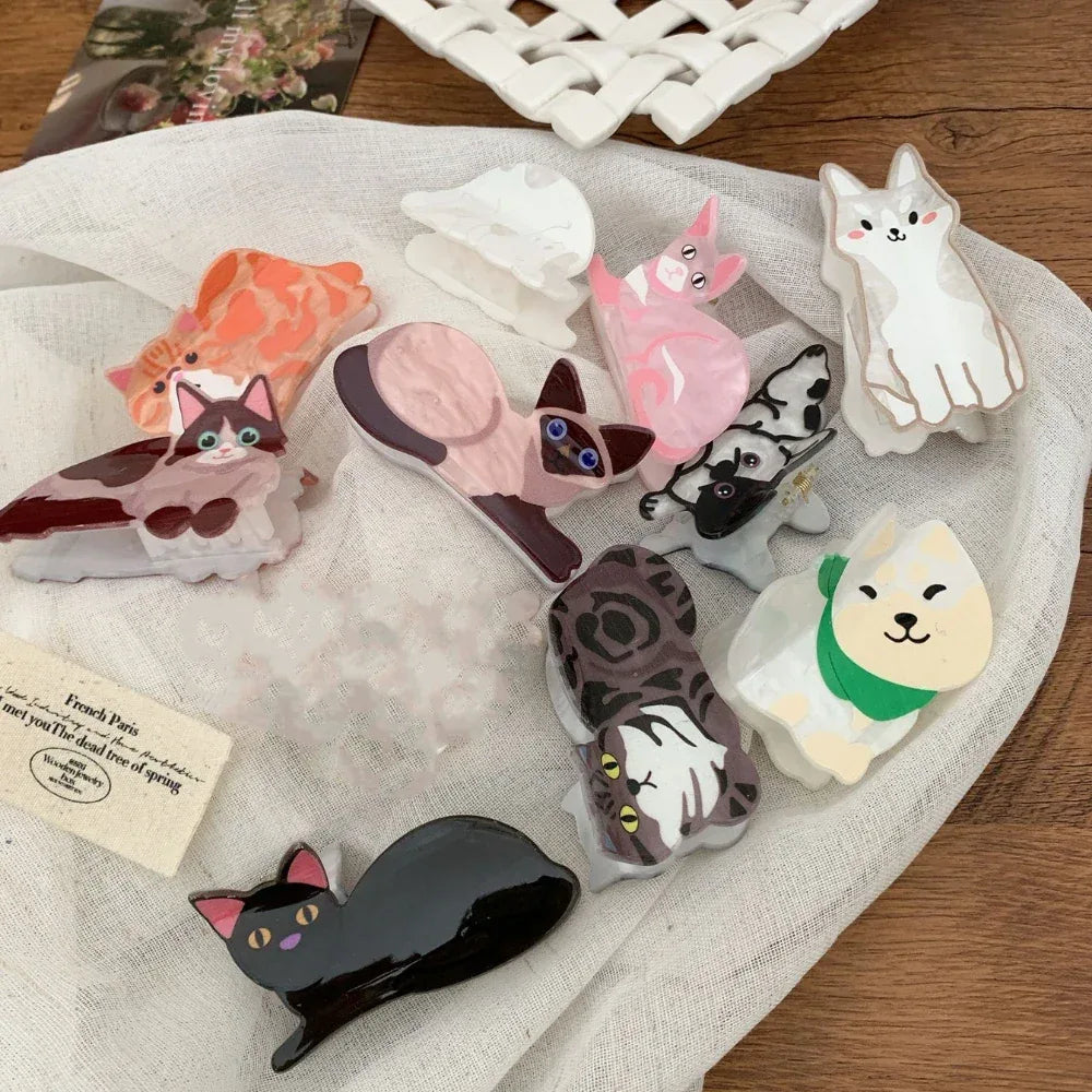 A variety of cat-shaped hair clips displayed on a white cloth.