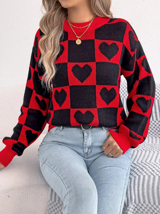 Woman wearing a red and black checkerboard heart print knitted sweater with light blue jeans