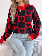 Woman wearing a red and black checkerboard heart print knitted sweater with light blue jeans