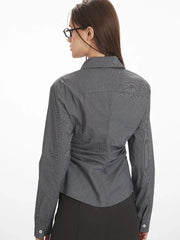 Back view of a woman wearing a grey long-sleeved button-down shirt with ruching detail.