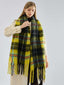 Woman adjusting her yellow and black plaid scarf over a cream coat.