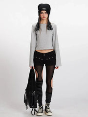 Model wearing a grey and white striped long-sleeved cropped top with flared sleeves, black shorts with cut-outs, black and grey striped thigh-high socks, and black sneakers. She is also wearing a black beanie and carrying a black bag.