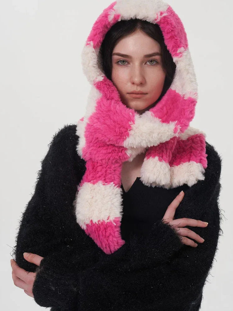 Close-up of a model wearing a black sweater and a pink and white striped fuzzy scarf, pulled up to cover her head like a hood.
