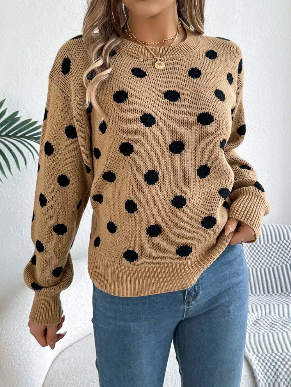 Woman wearing a brown polka dot sweater with blue jeans, close-up front view.