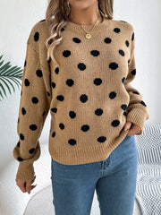 Woman wearing a brown polka dot sweater with blue jeans, close-up front view.