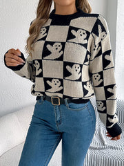 Woman adjusting her hair while wearing a black and white ghost print checkerboard knit sweater with blue jeans.