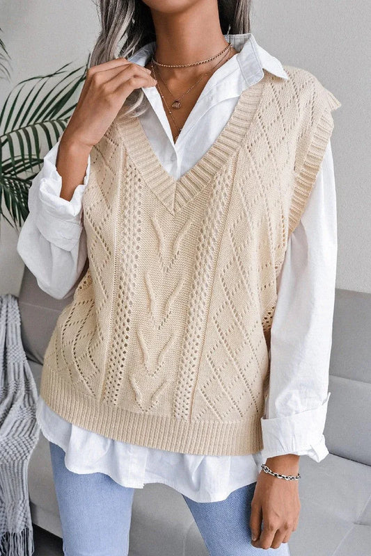 Woman wearing a cream knit V-neck sleeveless vest over a white collared shirt.