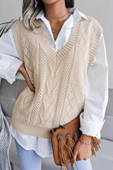 Close-up of a woman wearing a cream knit V-neck sleeveless vest over a white collared shirt, holding a brown fringed clutch.