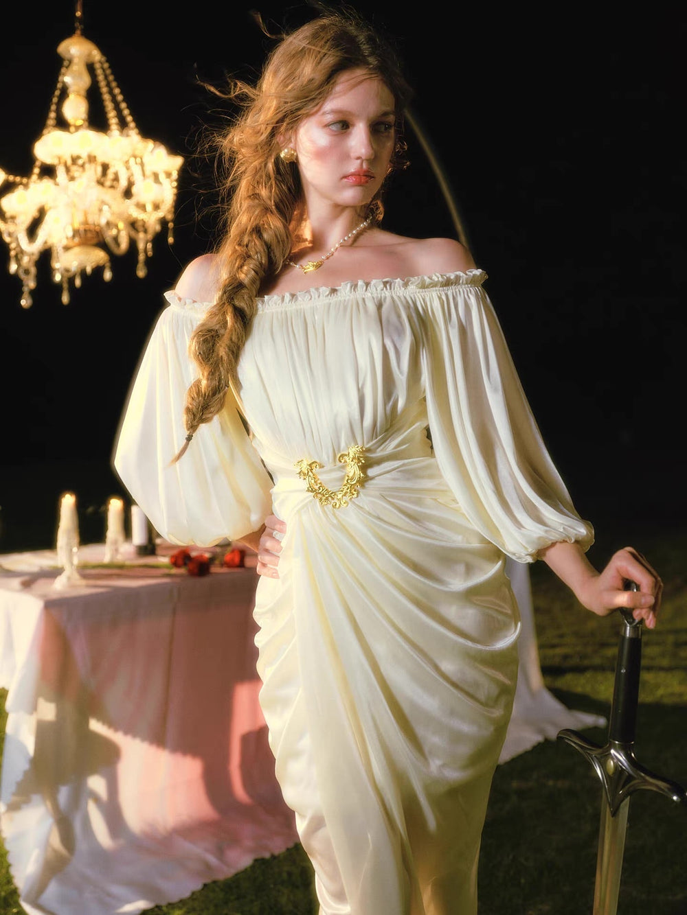 Full body shot of a woman in an elegant cream satin dress with an off-the-shoulder design, highlighting the ruched detailing and leg slit.