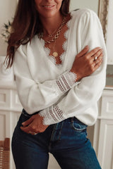 Woman wearing a white knit sweater with lace trim and blue jeans, arms crossed.
