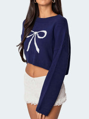 Side view of a navy cropped sweater with a white bow graphic print, worn by a woman.