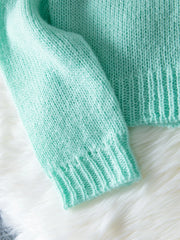 Close-up of the sleeve and ribbed cuff of a light mint green mohair blend cardigan.