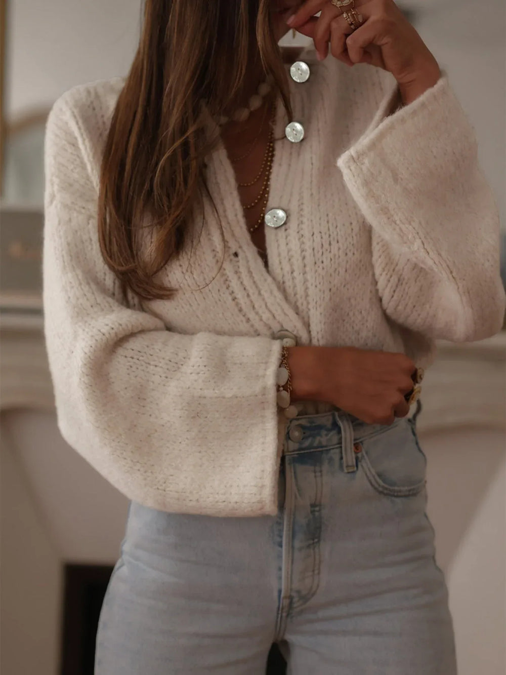 Side view of the model in the cream knit cardigan and denim, highlighting the silhouette and sleeve volume.