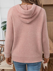 Back view of a woman wearing a pink knit hoodie and blue jeans.