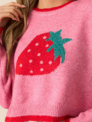 Detailed view of the strawberry graphic on a pink knit sweater.