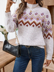 Woman wearing a white fuzzy knit sweater with a geometric Fair Isle pattern, dark wash jeans, and a black shoulder bag.