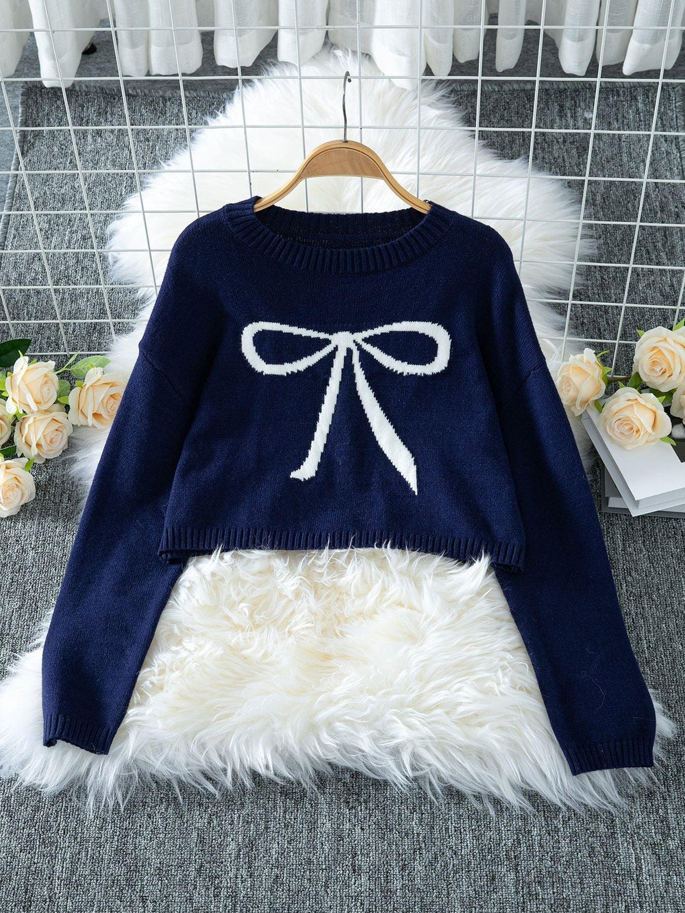 Navy cropped sweater with a white bow graphic print, displayed on a hanger.