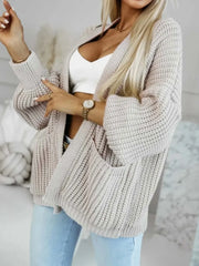 Close-up of a woman in a beige knit cardigan and white top