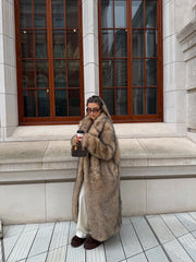 Full-length view of a woman in a long, plush faux fur coat with a lapel collar, paired with casual pants.