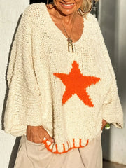 Woman with hands in pockets wearing an off-white knitted sweater with an orange star graphic