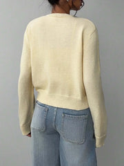 Back view of a model wearing a light yellow knit cropped cardigan and light-wash wide-leg jeans.
