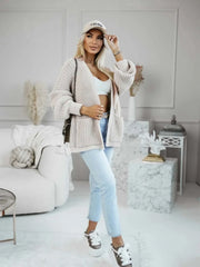 Full body shot of a woman in a beige knit cardigan, white top, and jeans