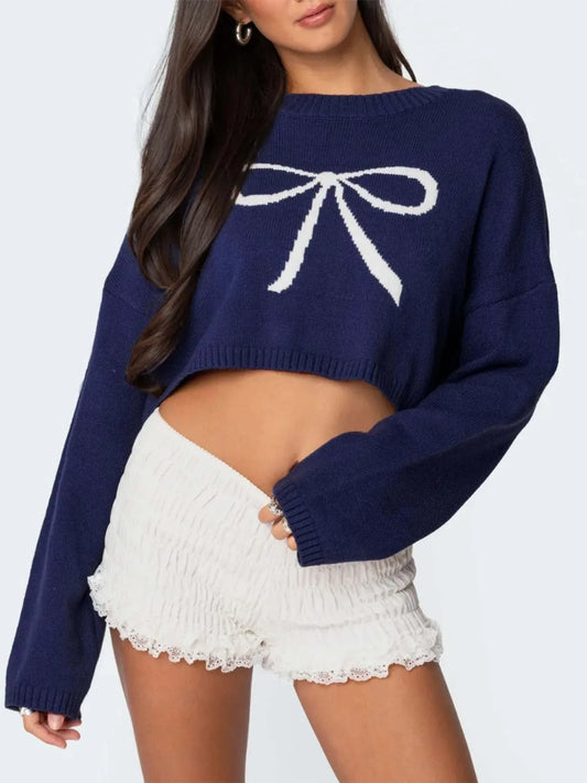 Navy cropped sweater with a white bow graphic print, worn by a woman with white ruffled shorts.